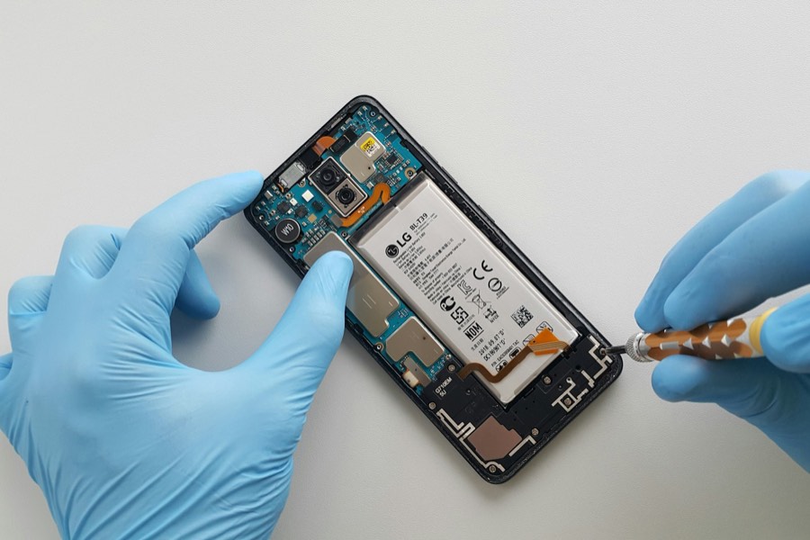 Des mains gantées ouvrent un smartphone pour le réparer
